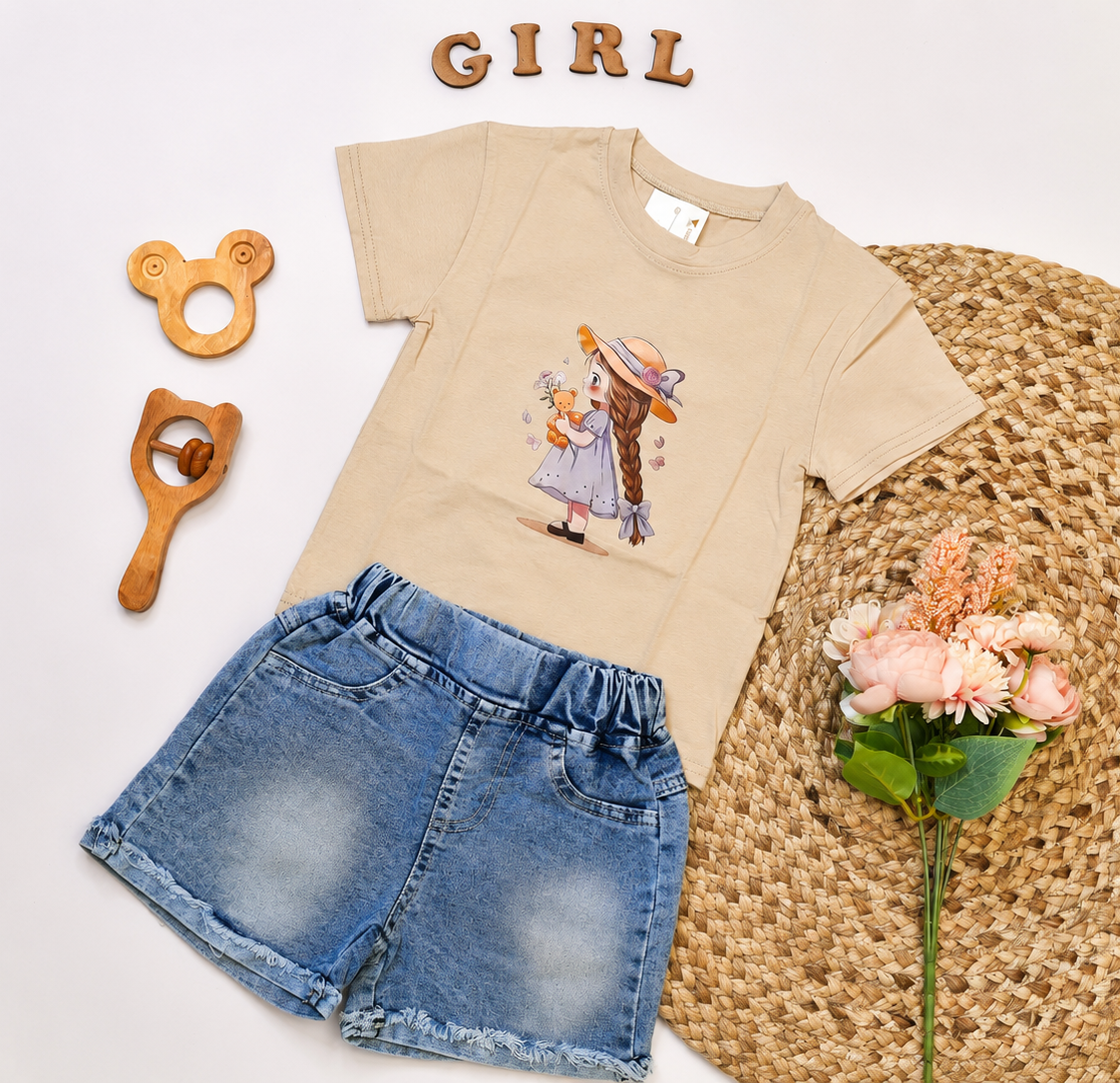 A children's outfit laid flat on a white background, featuring a beige short-sleeve T-shirt with a colorful cartoon girl graphic